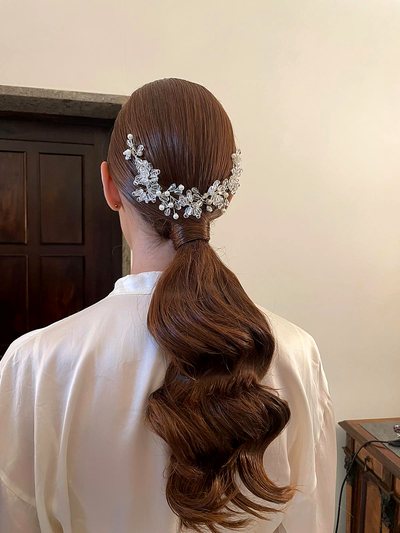 Coda bassa ondulata con accessorio gioiello, acconciatura da sposa
