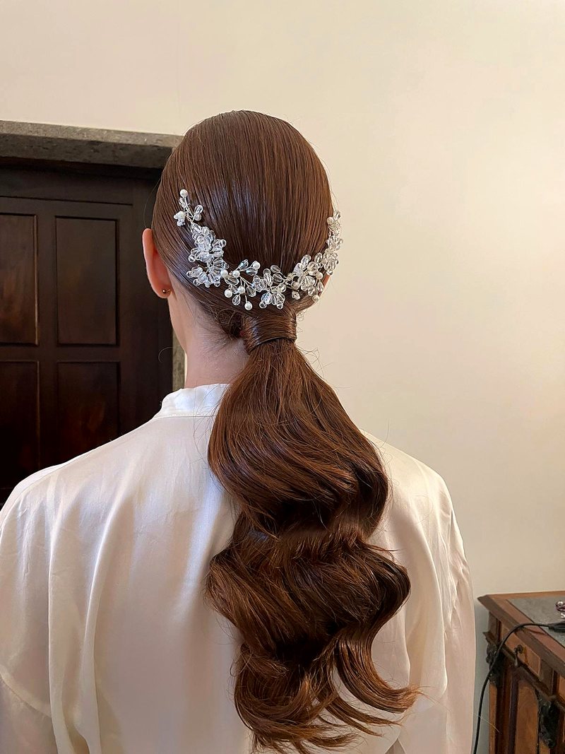 Coda bassa ondulata con accessorio gioiello, acconciatura da sposa