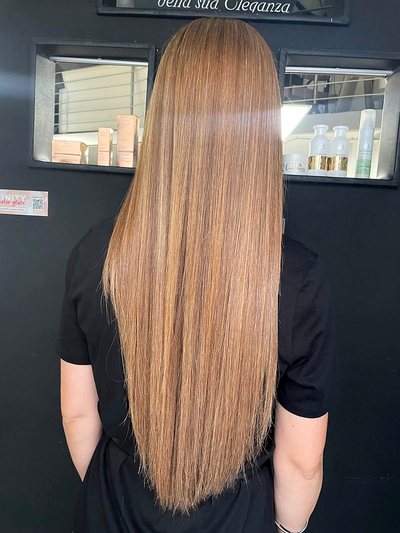 Capelli lunghissimi lisci color miele, visti di spalle davanti agli specchi del salone