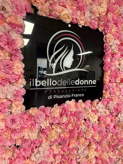 La targa con il logo Il Bello delle Donne incorniciata dalla parete di fiori rosa